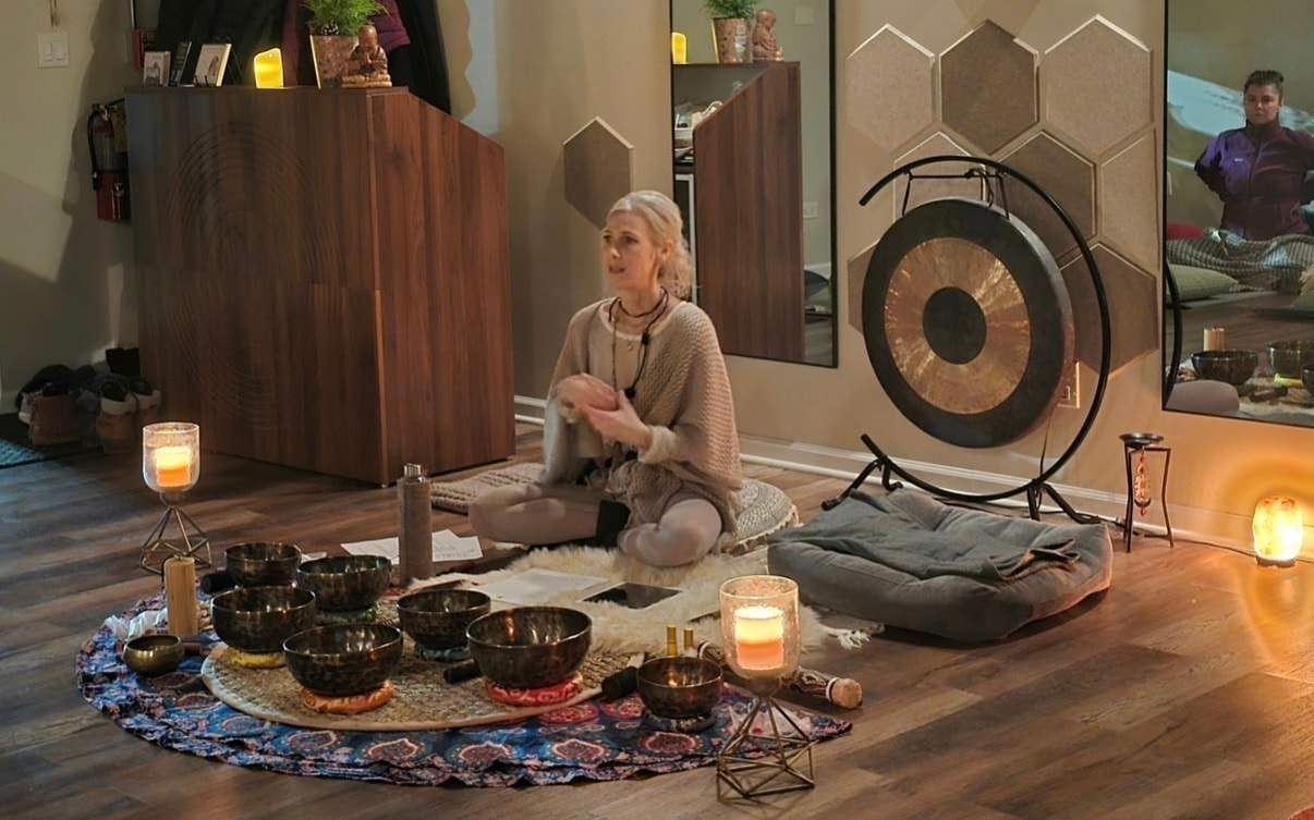 Ania Haas seated with Tibetan singing bowls and a gong inside Mindful Way Studio in Mokena, IL — a luxury wellness sanctuary offering sound healing, meditation, and holistic wellness classes
